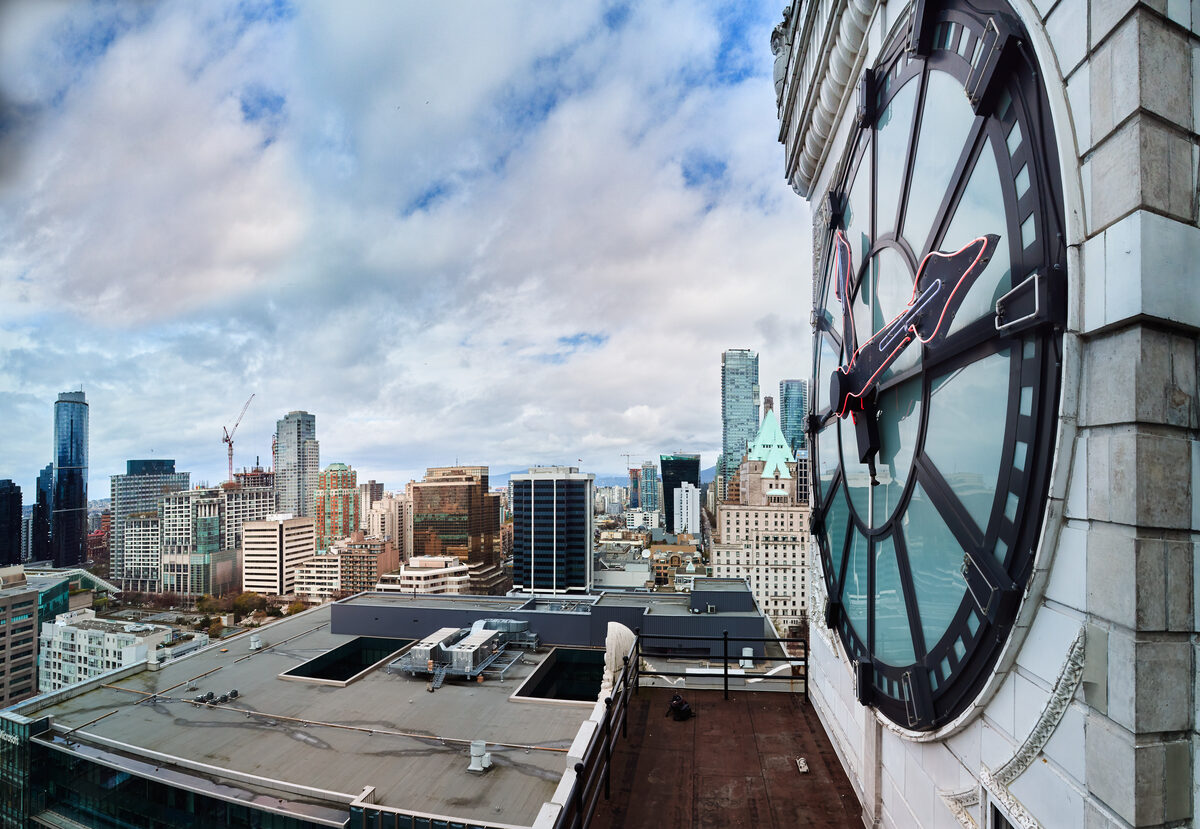 Close-up of one of the four clock faces with the Vancouver city skyline visible behind