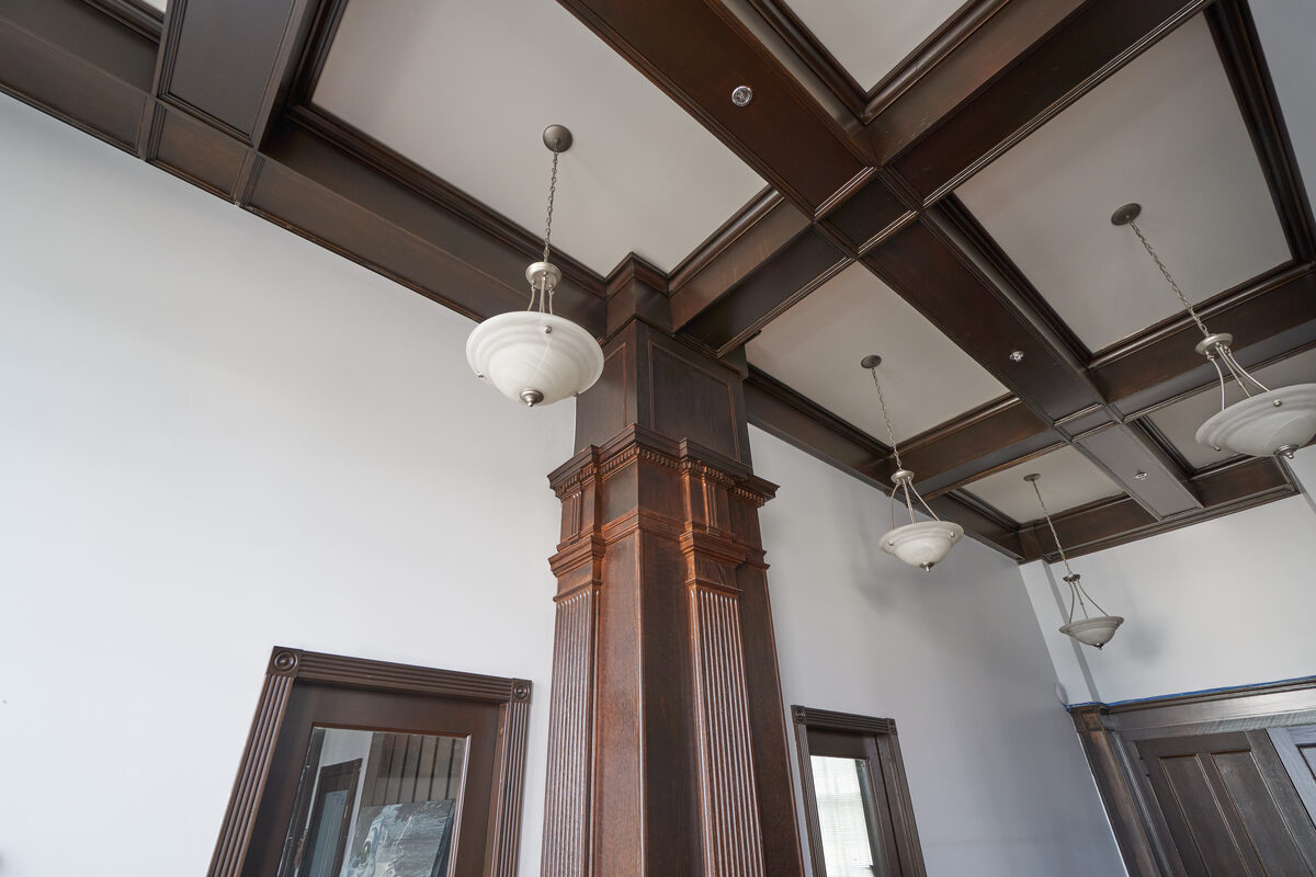 Dark wood coffered ceiling and fluted columns in the lobby with period globe light fixtures