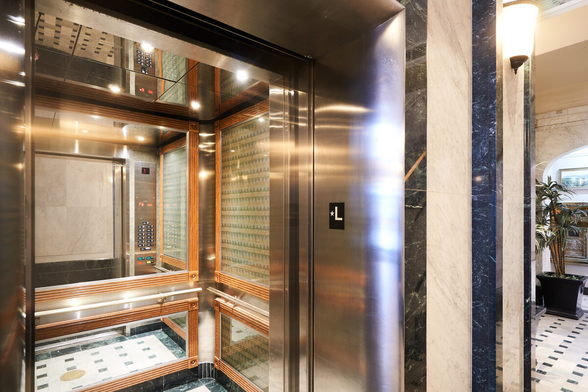 Elevator doors with marble surround and checkerboard floor tiles in the building lobby