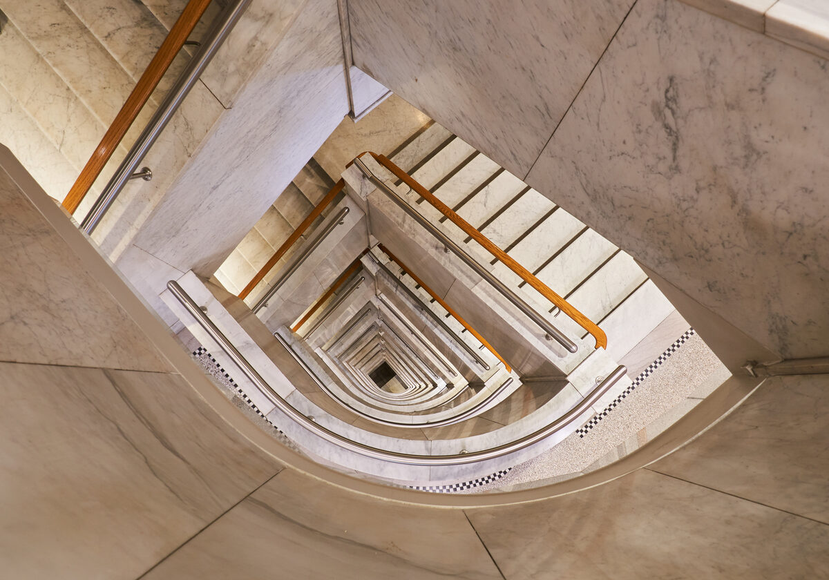 Looking down through the marble stairwell with oak handrails spiraling down multiple floors
